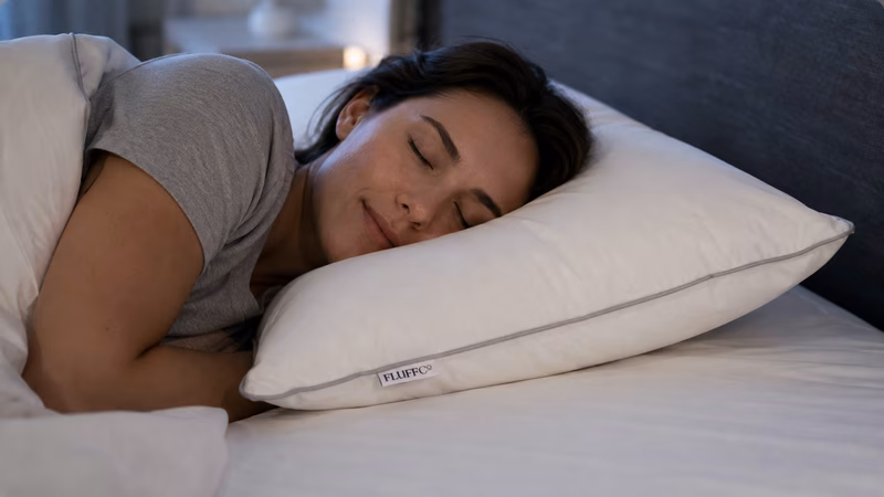 Close-up of a fluffy white pillow with elegant blue piping.